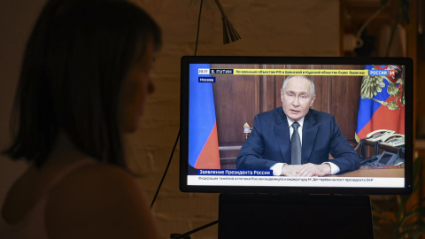 Una mujer mira un discurso televisado del presidente ruso Vladimir Putin, en Moscú, Rusia.