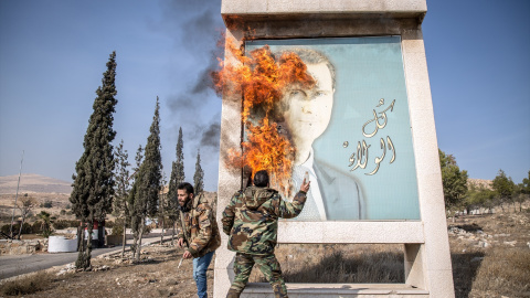 Dos hombres queman una imagen de Al Asad en Damasco.