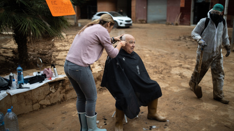 Una mujer corta el pelo a un vecino de Paiporta (Valencia), varias semanas después de la dana.