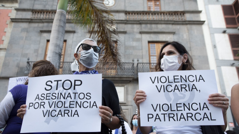 Dos personas con carteles contra la violencia vicaria en una protesta contra la violencia machista.