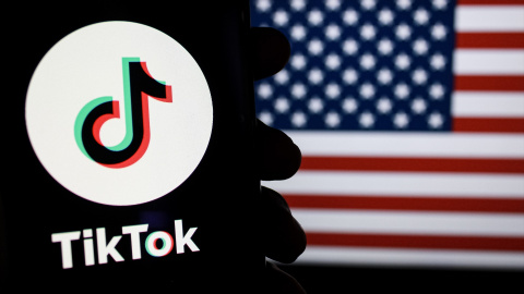 Imagen del logotipo de TikTok en un teléfono inteligente con la bandera de América de fondo.