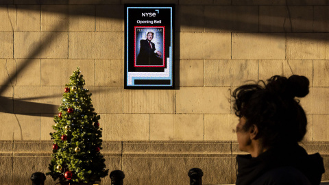 Una persona pasa junto a una pantalla con una imagen del presidente electo de Estados Unidos, Donald Trump, en el exterior de la Bolsa de Nueva York (EE.UU.).