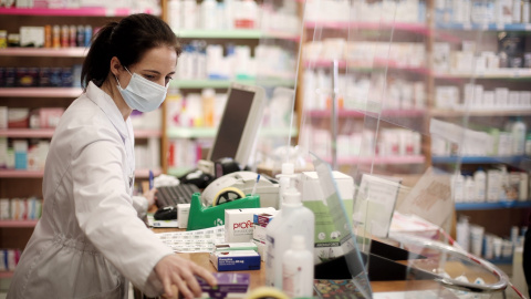 Una farmacéutica con mascarilla despacha en una farmacia de Madrid, en una imagen de archivo.