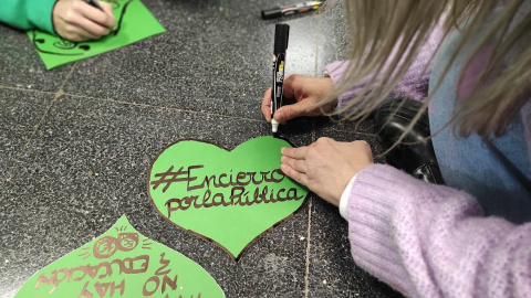 Los manifestantes, durante su encierro, escriben carteles de 'Encierro por la pública'