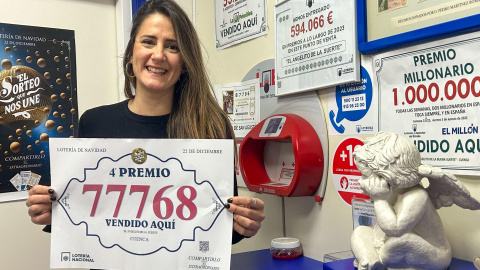 Una mujer muestra el número 77768, premiado con un cuarto premio de la Lotería de Navidad.