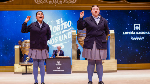 Las niñas de la Residencia San Ildefonso de Madrid Yadira Quinde Mendoza (i) y Kiara Román Benítez (d) muestran el número 45.225, uno de los quintos premios, durante el sorteo de la Lotería de Navidad que se celebra este domingo en el Teatro Real, en Madrid