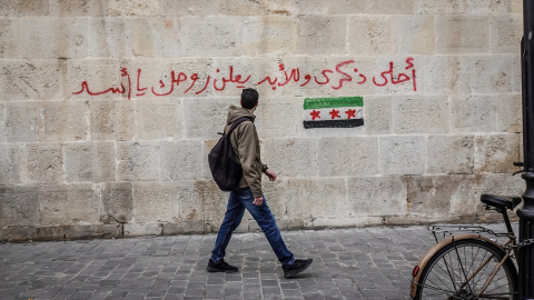 Un hombre camina por una calle de Damasco en Siria. En la pared puede leerse: "Maldito seas para siempre, Assad". Imagen de archivo.