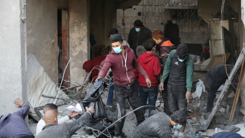 Varias personas buscan víctimas entre los escombros de una vivienda familiar bombardeada en Gaza.