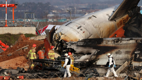 Bomberos trabajan entre los restos del avión de Jeju Air en el aeropuerto de Muan, Corea del Sur.