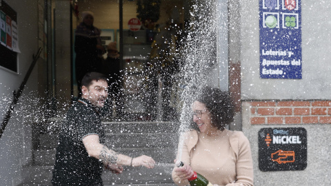 Beatriz Rodríguez, dueña de la administración de San Sebastián de los Reyes que ha vendido parte del número 06.766 agraciado con el segundo premio, abre una botella para celebrarlo.