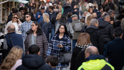 Varias personas observan el ambiente navideño en la Fira de Santa Llúcia de Barcelona, en la plaza de la Catedral, a 5 de diciembre de 2024, en Barcelona.