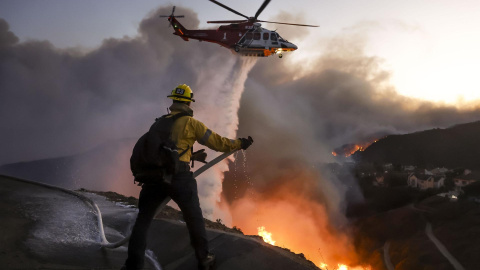 Los bomberos del condado de Los Ángeles utilizan mangueras y agua desde un helicóptero para combatir el incendio forestal en California, EE.UU.