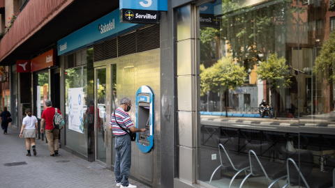 Un hombre saca dinero en un cajero, en una foto de archivo.