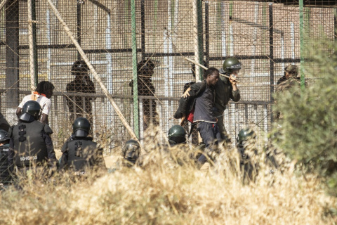 Un miembro de las fuerzas de seguridad marroquíes conduce desde suelo español a uno de los migrantes que lograron saltar la valla de Melilla. -Javier Bernardo