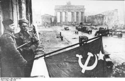 Soldados soviéticos triunfantes fijan una bandera en el hotel Adlon de Berlín, frente a la emblemática Puerta de Brandenburgo, el 10 de mayo de 1945. Imagen: Bundesarchiv.