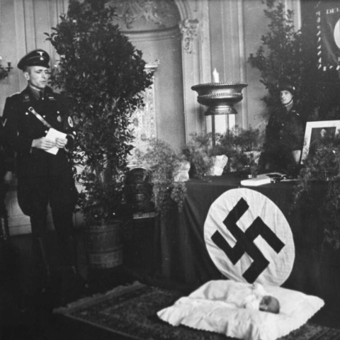 Bautizo en Lebensborn, la organización de las guarderías nazis, ante un retrato de Hitler.