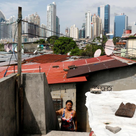 Una mujer sale de su vivienda en una barriada popular en la ciudad de Panamá, con el distrito financiero al fondo. REUTERS/Carlos Jasso