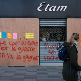 Una joven pasa junto a una pintada en París, que dice "Nosotros ganaremos la guerra contra el capitalismo". AFP/Francois Guillot