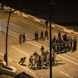  La Policía marroquí se forma mientras migrantes protestan contra que se les impida cruzar la frontera en la ciudad norteña de Fnideq, cerca de la frontera entre Marruecos y el enclave español de Ceuta, en el norte de África, el 19 de mayo de 2021.- 