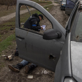  Agentes de Policía investigan el cuerpo de una mujer civil muerta que yace en el suelo junto a un automóvil, en Bucha,, el 6 de abril de 2022.- EFE