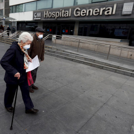 Una pareja de ancianos pasa ante el Hospital de La Paz, en Madrid. EFE/Mariscal