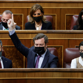  El portavoz de Vox en el Congreso, Iván Espinosa de los Monteros, alza la mano en presencia del líder del partido, Santiago Abascal, y de la portavoz adjunta Macarena Olona durante la sesión plenaria del Congreso de los Diputados el pasado 17 de febre