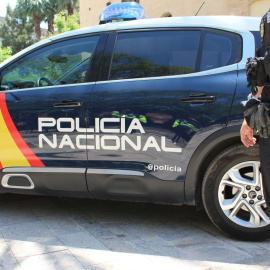 Un agente de la Policía Nacional junto a un vehículo policial. EFE