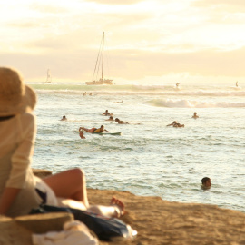 Imagen de una mujer mirando al mar mientras muchas personas disfrutan. Foto: dpung / Pixabay