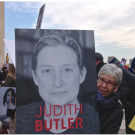 La historiadora Joan Scott sostiene una pancarta con el rostro de la filósofa Judith Butler en una manifestación en París. Imagen de archivo.