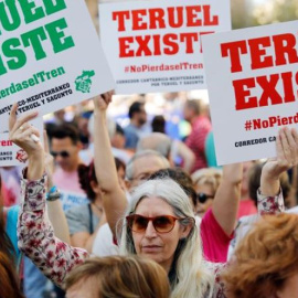  Una manifestante exhibe sendos carteles con el lema "Teruel existe" durante una manifestación convocada en València para reivindicar la necesidad de "no perder el tren" del Corredor Cantábrico-Mediterráneo,en la que han pedido inversiones en el tramo