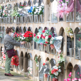 Una mujer deposita flores en un nicho en un cementerio del Poblenou en Barcelona, este lunes 1 de noviembre. / Marta Pérez - EFE