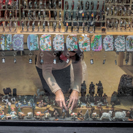 Una mujer coloca decoración navideña en el escaparate de una tienda de “souvenirs” del centro de València. EFE/Biel Aliño