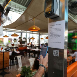 Un joven consulta la carta de productos con código QR en un bar / EFE