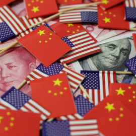 Billetes de dólar y de yuan, entre banderas de EEUU y de China.. REUTERS/Jason Lee/Illustration