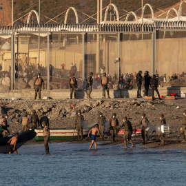  Miembros del ejército ayudan a dos inmigrantes a su llegada a la playa de El Tarajal, junto a la valla fronteriza , en Ceuta este miércoles.- EFE