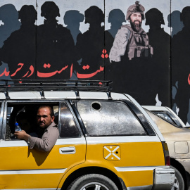  Un hombre mira por la ventanilla de un automóvil mientras los viajeros avanzan por una carretera en Kabul el 5 de septiembre de 2021. A las pocas semanas de que los talibanes tomaron la capital, muchas de las obras de arte callejero han sido pintadas, r