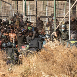  Un miembro de las fuerzas de seguridad marroquí se lleva detenido a un migrante desde el lado español de la frontera con Melilla. — Javier Bernardo