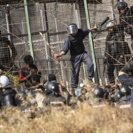 Un agente marroquí golpea desde territorio español con un palo a los migrantes que lograron saltar la valla de Melilla. -Javier Bernardo