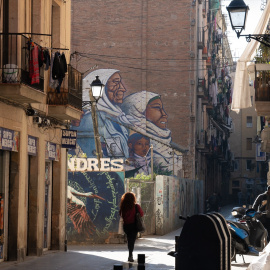 Dos personas caminan por una calle céntrica, a 24 de enero de 2024, en Barcelona, Catalunya (España), frente a un mural que presenta a personas migrantes.- David Zorrakino / Europa Press