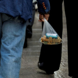 Un home porta una bossa de plàstic amb noves monedes d'euro, el 15 de novembre del 2022. Foto: REUTERS/Jon Nazca