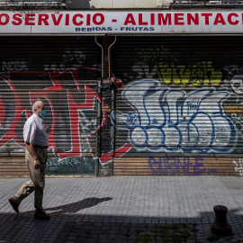 Un hombre protegido con mascarilla camina ante un comercio cerrado en una céntrica calle de Sevilla, durante el confinamiento decretado en el Estado de Alarma debido a la crisis sanitaria de la covid-19. EFE/Julio Muñoz