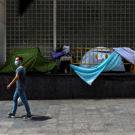 Un home passa davant de diverses tendes de campanyes de persones sense llar, aquest dimecres al centre de Barcelona. EFE/ Enric Fontcuberta