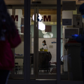 Las puertas de un hospital madrileño muestran personas esperando con mascarillas y guantes y una trabajadora sanitaria. / JAIRO VARGAS