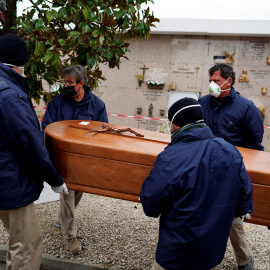 Los empleados de una morgue llevan el ataúd de una persona que murió por la enfermedad del coronavirus (COVID-19), durante el cierre parcial para combatir el brote de la enfermedad, en el cementerio de Carabanchel en Madrid, España, el 27 de marzo de 2