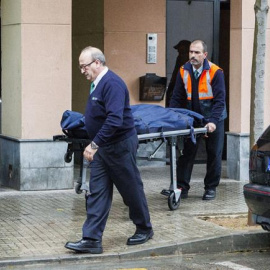 Miembros de los servicios funerarios trasladan los restos mortales de la mujer  fallecida en su piso del barrio de Son Cladera, en Palma. - EFE