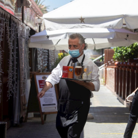 27/05/2020.- Un camarero lleva su pedido a unos clientes a una de las terrazas del Puerto Olímpico de Barcelona. / EFE