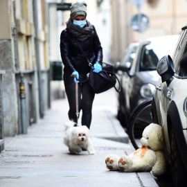 Una mujer con mascarilla pasea a su perro durante la crisis del coronavirus. (Reuters)