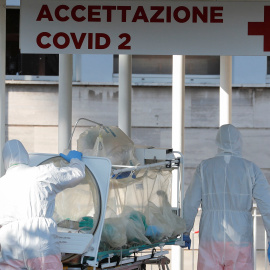 Dos sanitarios trasladan a un enfermo con coronavirus a un hospital en Roma./ REMO CASILLI (REUTERS)