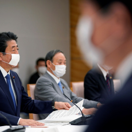 El primer ministro de Japón, Shinzo Abe, con mascarilla, con otros miembros de su gabinete para analizar las medidas frente a la pandemia del coronavirus. REUTERS/Franck Robichon