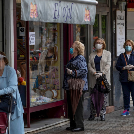 12/05/2020.- Varias mujeres con mascarillas hacen cola ante una mercería en el barrio de Triana de Sevilla, hoy martes en el segundo día de la fase 1 de desescalada en la que diferentes actividades han podido retomar su actividad desde que se inició el